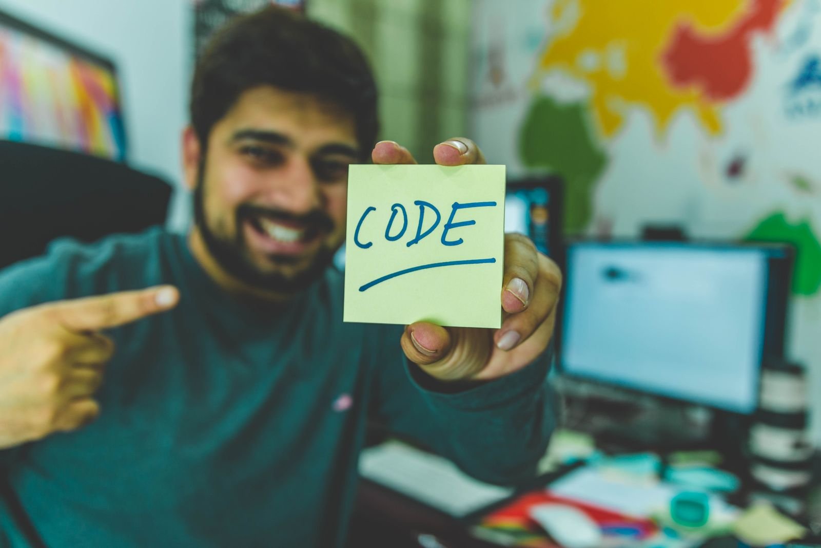 Smiling developer holding a sticky note that says code