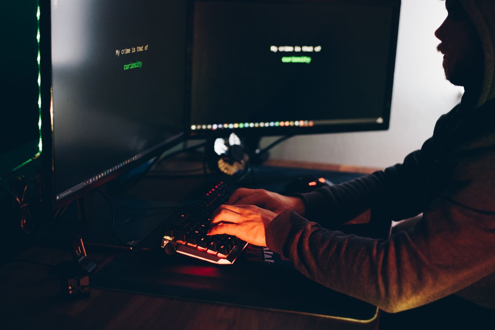 Developer typing on a backlit keyboard in a dark room