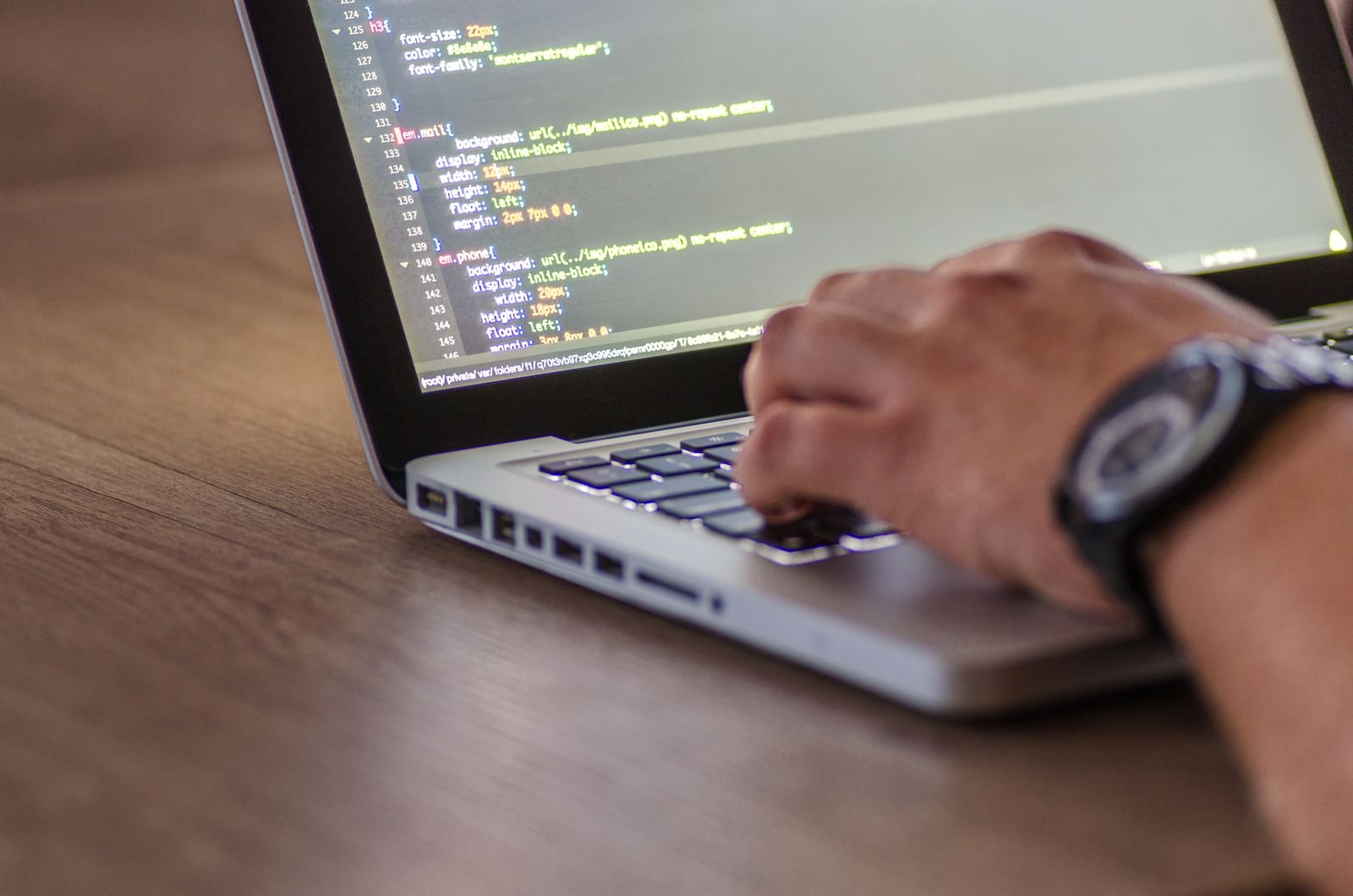 Hands typing code on a laptop keyboard