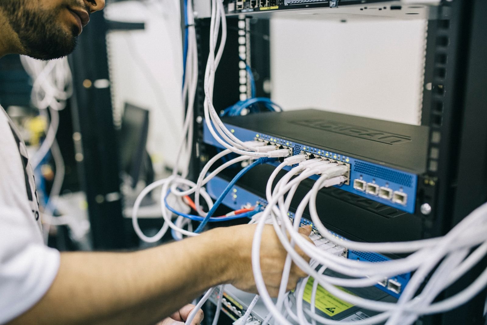 Technician patching cables in a network rack